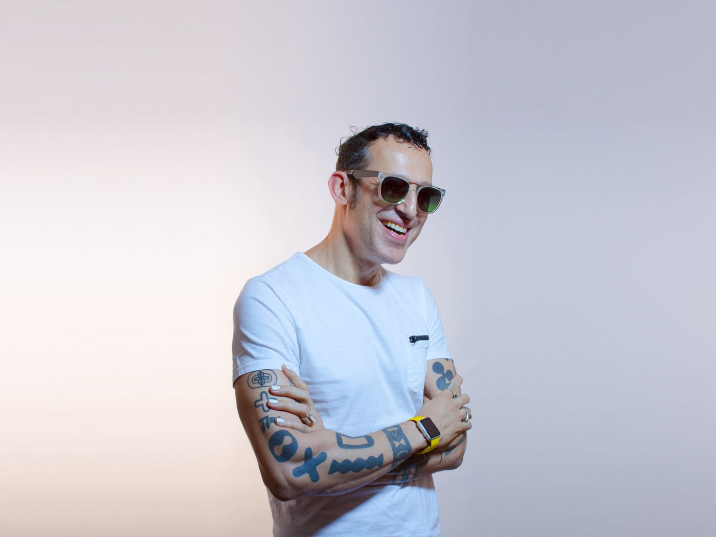 Portret oficial al designerului Karim Rashid, în tricou alb, cu tatuajele vizibile
