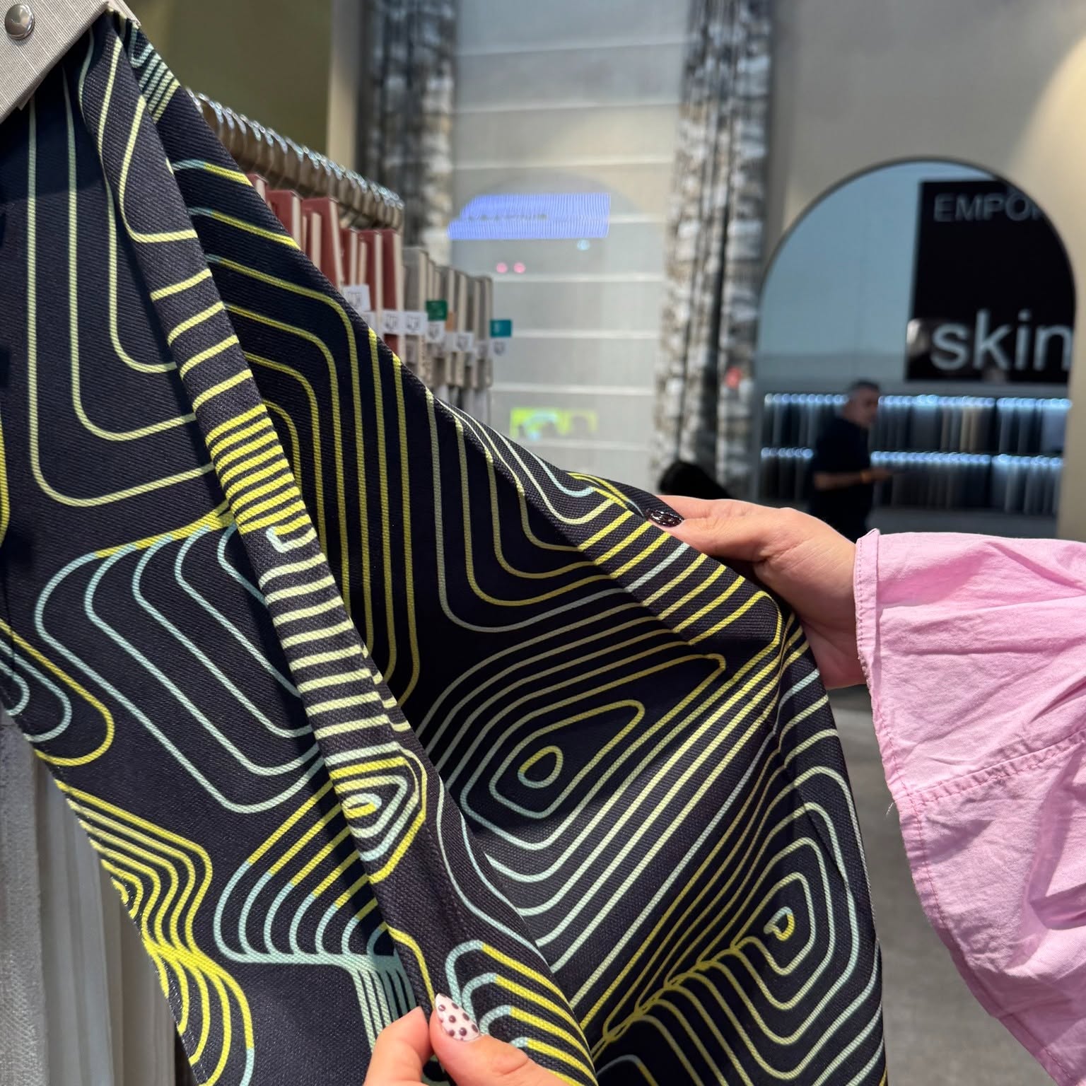 Detaliu de material textil cu linii fluide galben lime și albastru pe fundal negru, prezentat la Deco Days